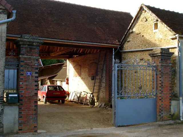 There are brick houses, pipes, blue gate, ladder, bicycles, red car and trees at the back.