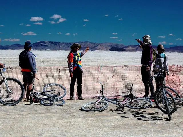 In this picture we can find five persons, all are standing and we can also find some bicycles, net,...